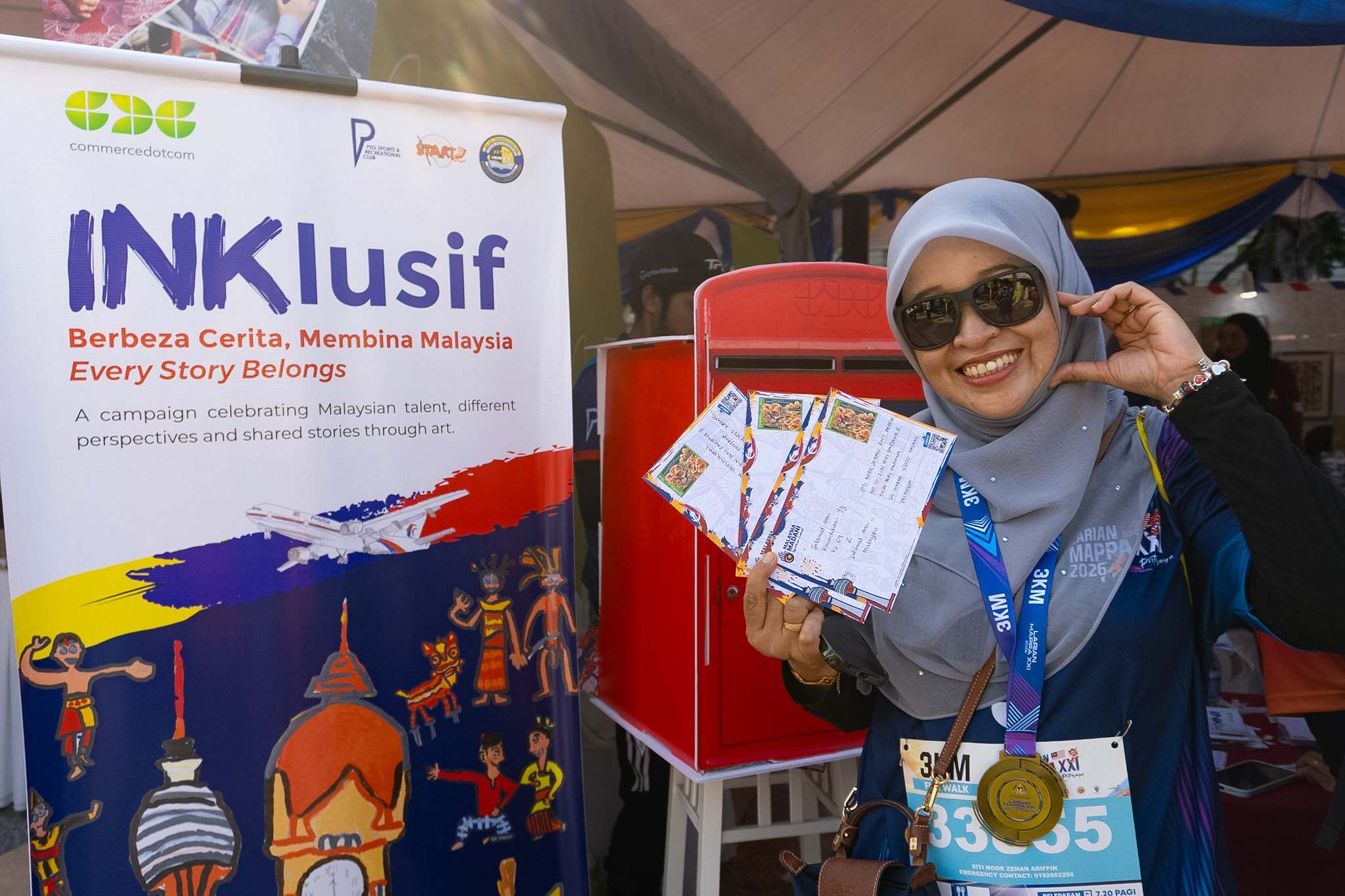 A Larian MAPPA participant holds INKlusif postcards beside the campaign display.